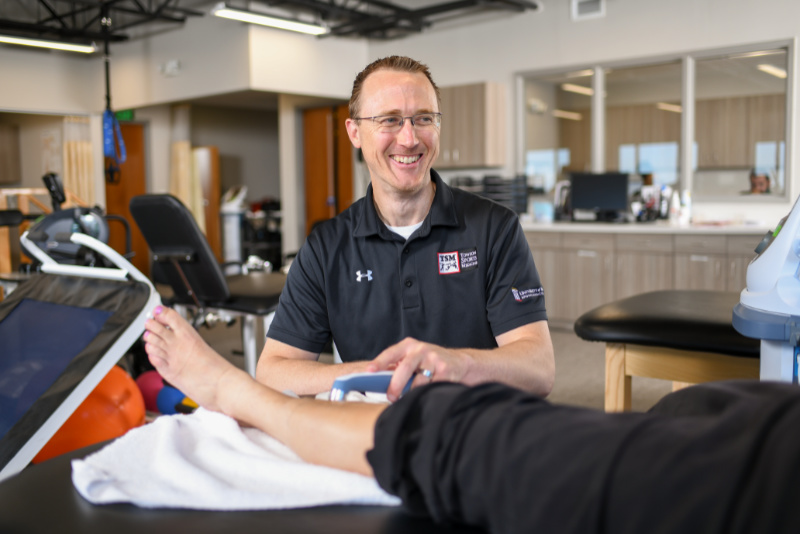 physical therapist performing therapy on patients lower leg