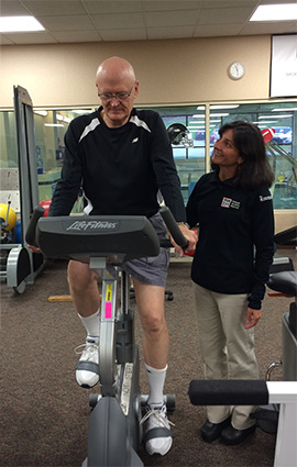 Physical therapist assisting senior on an exercise bike