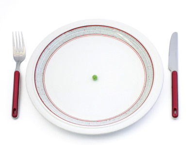 plate, fork and knife with one pea in the center of the plate